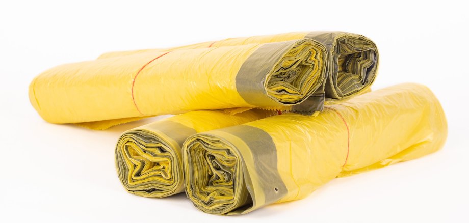 Rolls of yellow trash bags on white background