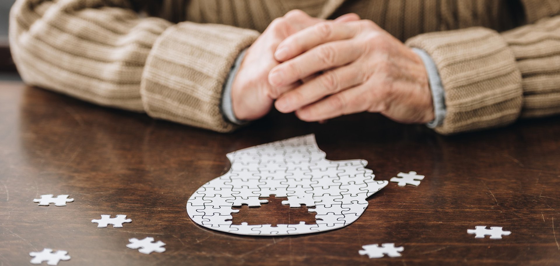 cropped view of senior man playing with puzzles on table