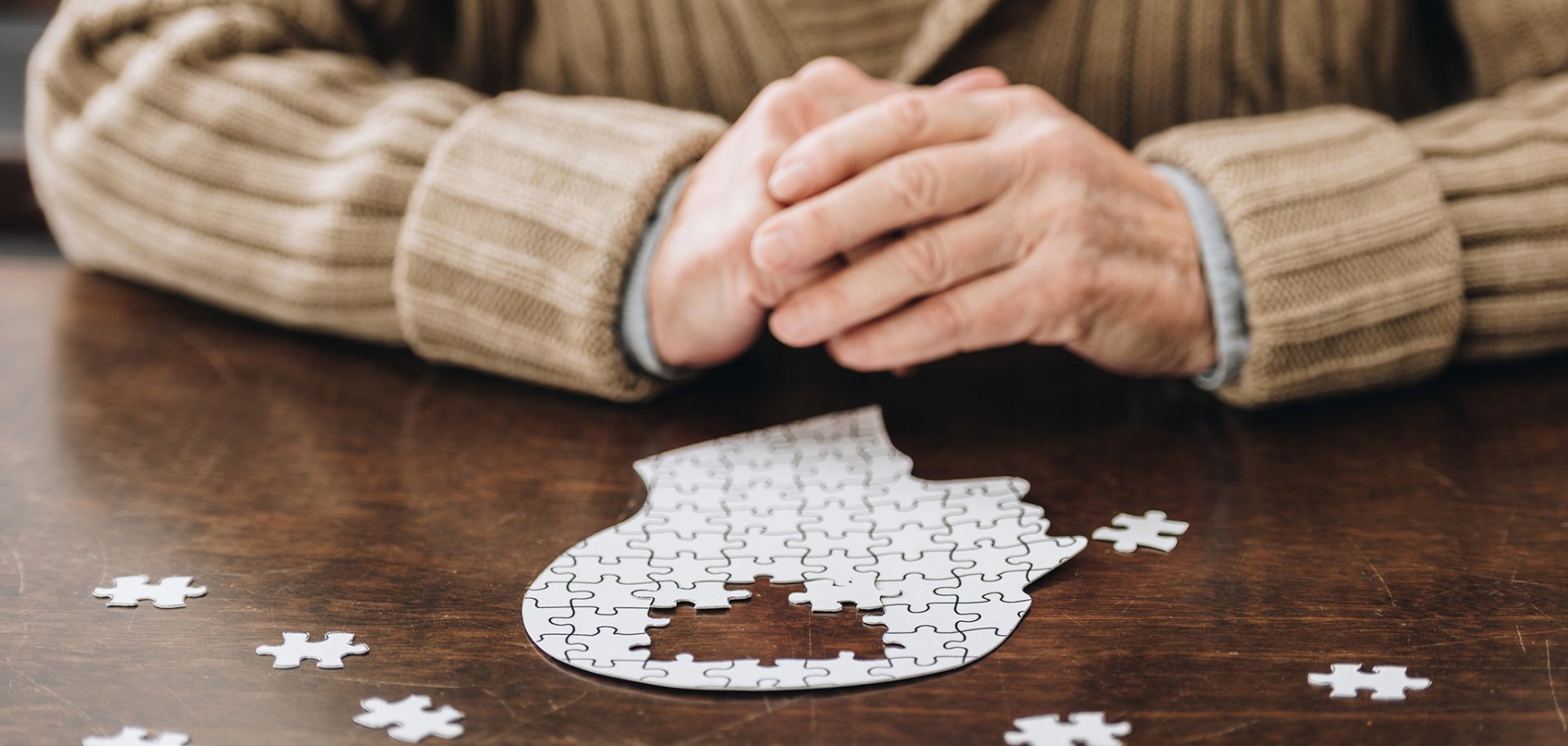 cropped view of senior man playing with puzzles on table