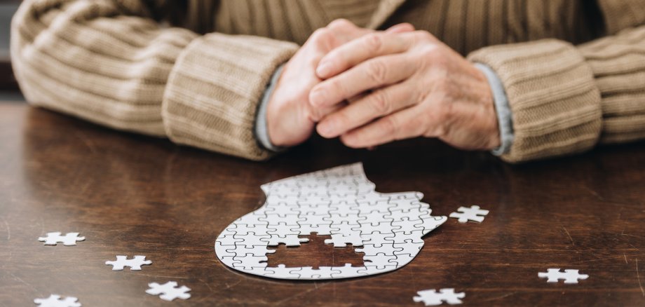 cropped view of senior man playing with puzzles on table cropped view of senior man playing with puzzles on table