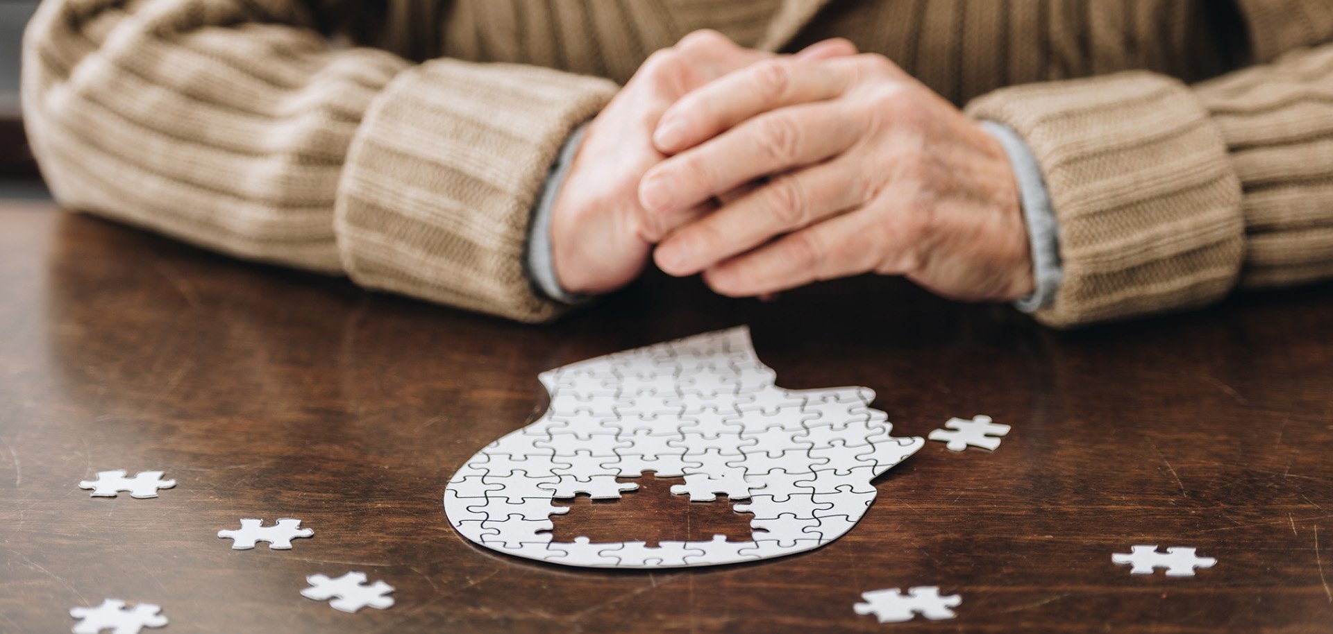 cropped view of senior man playing with puzzles on table