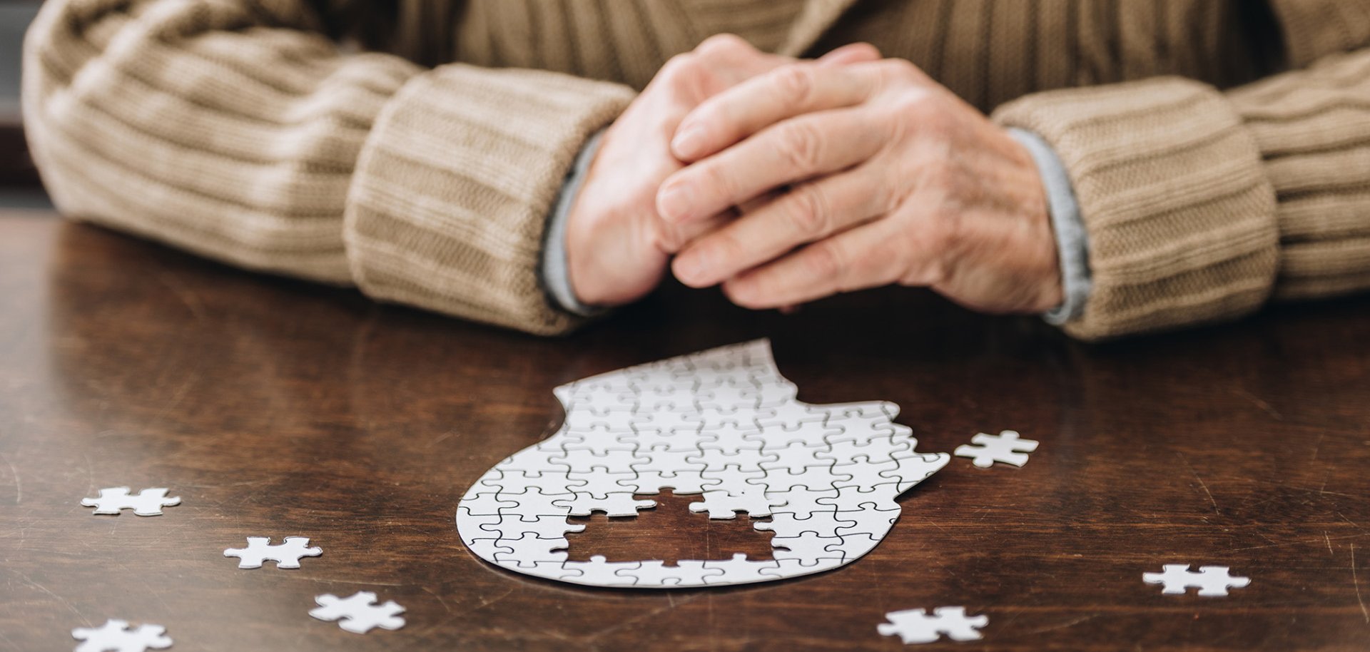 cropped view of senior man playing with puzzles on table cropped view of senior man playing with puzzles on table