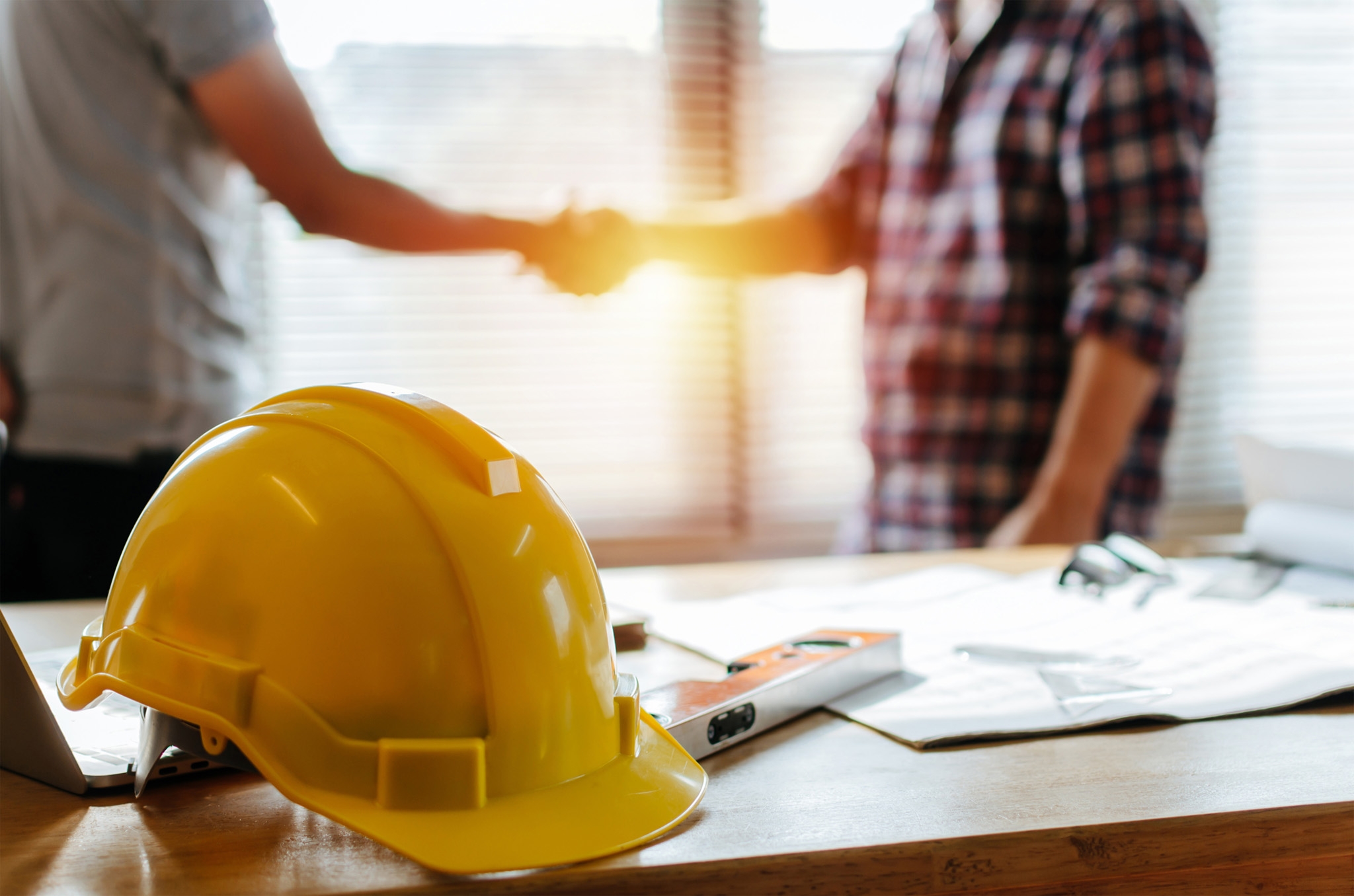 yellow safety helmet on workplace desk with construction worker