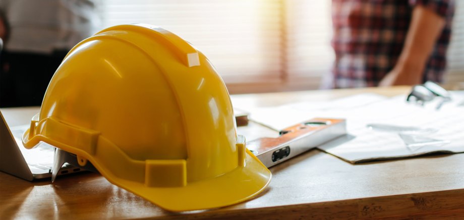 yellow safety helmet on workplace desk with construction worker
