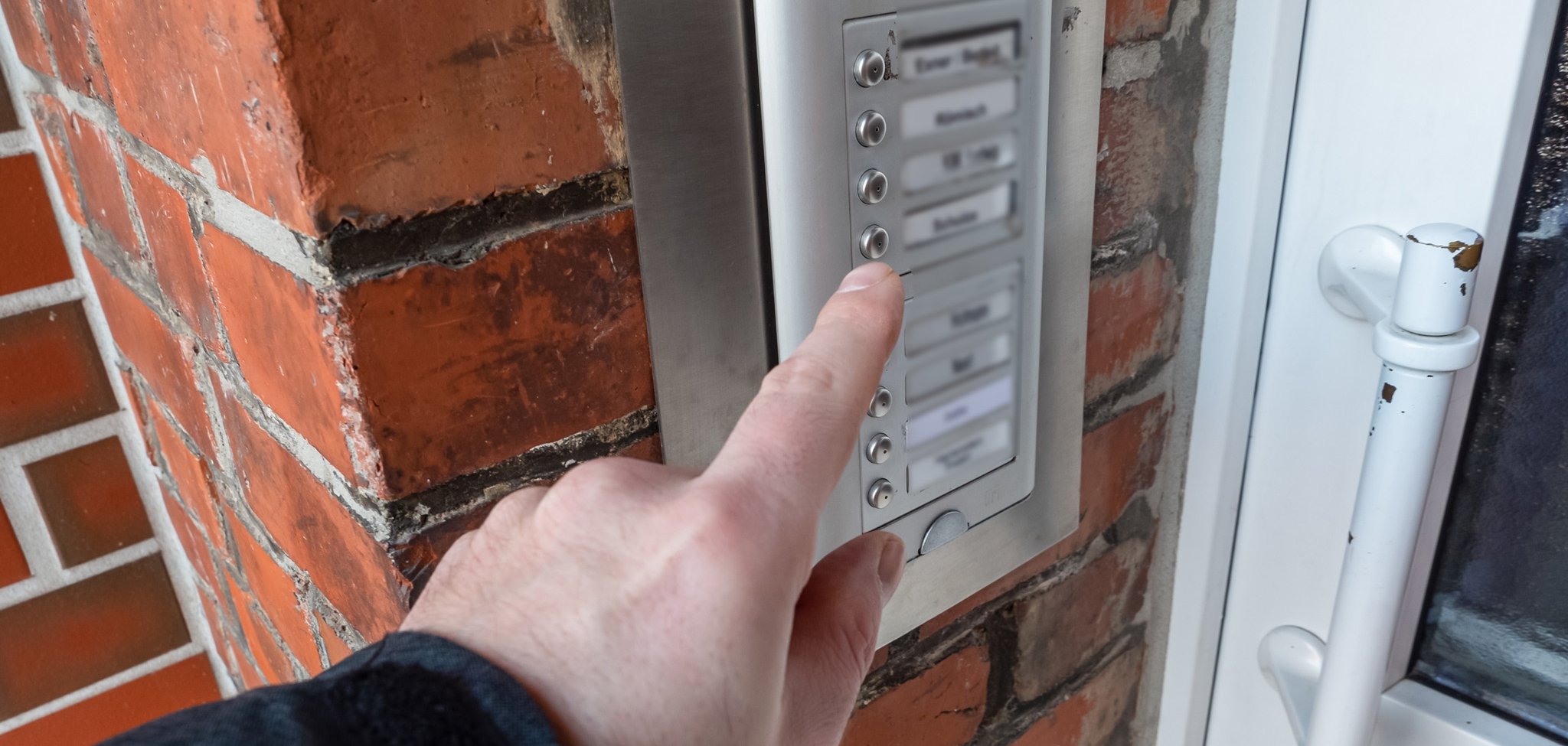 Mann klingelt an einer Klingelanlage