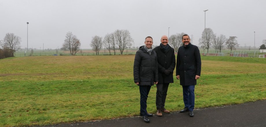 Ungenutzter Hartplatz unterhalb des Kunstrasenplatzes am Sportzentrum. Von links: Bürgermeister Steffen Bonk, Alexander Thomas, Geschäftsführer der PHORMS Schule und Erster Stadtrat Lars Knobloch